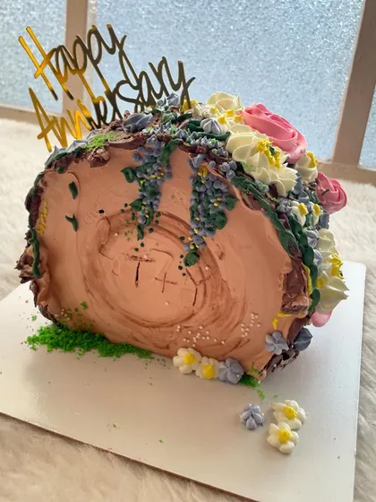 An enchanted forest-themed top-forward cake. The wood-like texture and cascading sugar flowers create a magical, storybook feel.