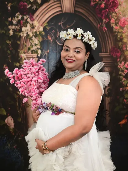 A happy mom-to-be in our white ruffle gown, accessorized with a floral crown for a fresh and beautiful studio maternity portrait.
