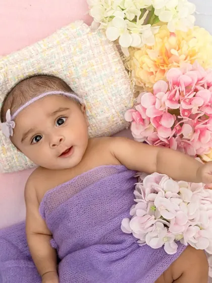 The combination of the soft purple wrap and the surrounding pastel flowers beautifully complements this baby's alert expression. This shot shows how I incorporate color to enhance the mood of the portrait.