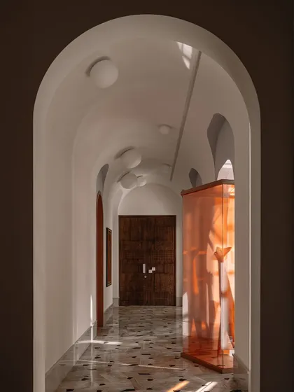 A straight-on view of the galleria, where a sculpture by Vyomasura is framed within a deep amber storefront, creating a striking focal point.