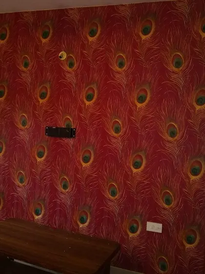 A bold red wallpaper with a repeating peacock feather motif. This vibrant design makes a powerful statement in this room.
