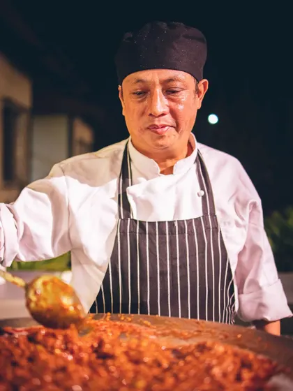 A chef prepares a flavourful dish on a large tawa at one of our live Indian cooking stations.