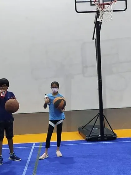 A group of players stands ready with their basketballs, listening to the coach before the next drill.