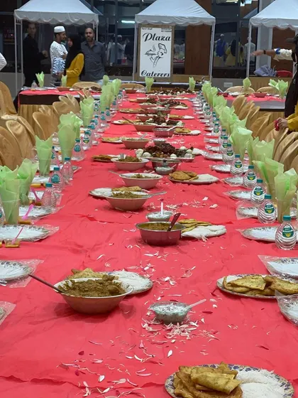 A festive meal setup at the Royal Convention Hall. The tables are beautifully arranged with green napkins and a full spread, ready for guests to celebrate together.