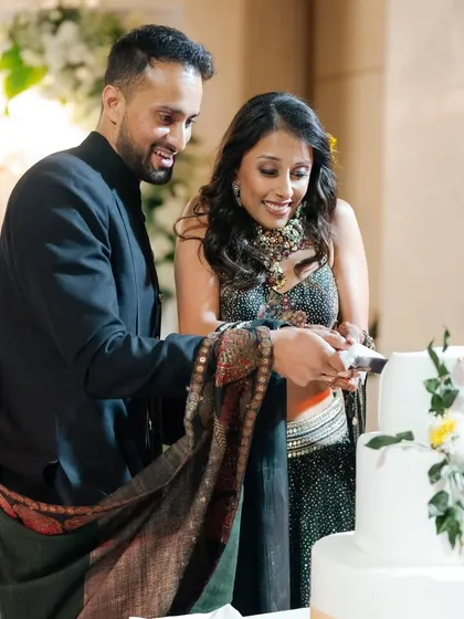 The sweet moment of the cake-cutting ceremony. The couple's shared smile as they slice into their elegant, floral-adorned wedding cake marks the beginning of their sweet journey together.