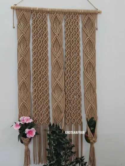 A full view of the large, three-pot macrame plant hanger. This piece is a great decor option for a studio, boutique, or cafe, adding a touch of natural, bohemian style. It's customizable in different sizes and colors.