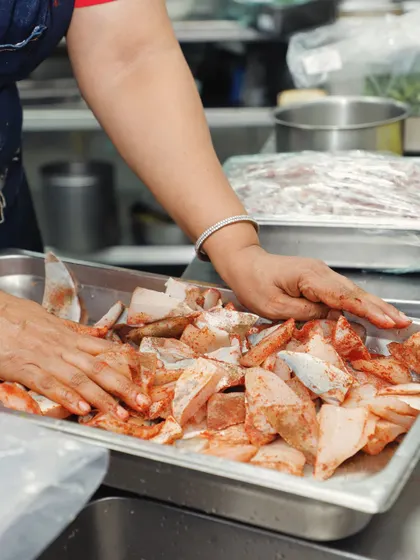 Marinating fresh fish by hand. This allows me to ensure every piece is perfectly coated in our signature masala blend, a crucial step for dishes like our Pollichathu and fish fry.