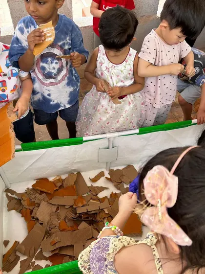 Children tear up cardboard to add to the compost bin, learning about which materials are biodegradable.