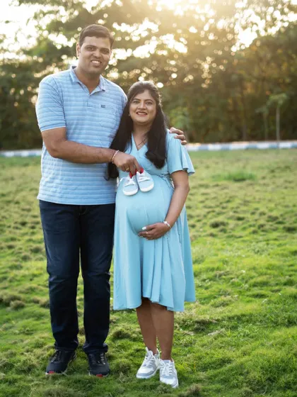 A classic outdoor family portrait. The golden hour lighting and natural green background create a warm and happy atmosphere.