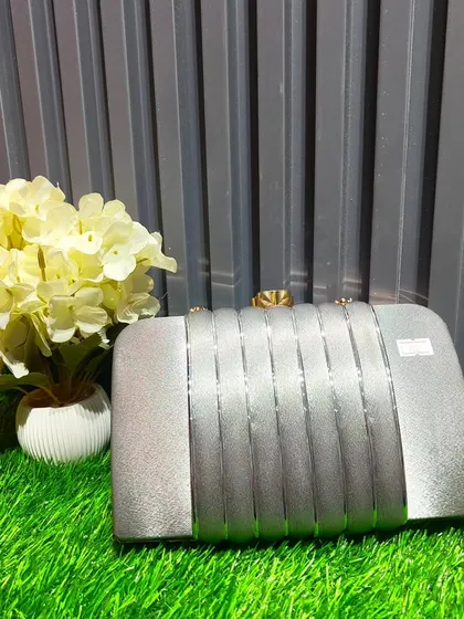 A sleek silver hard-case clutch. Its minimalist design makes it a versatile accessory that can be paired with almost any colorful outfit.
