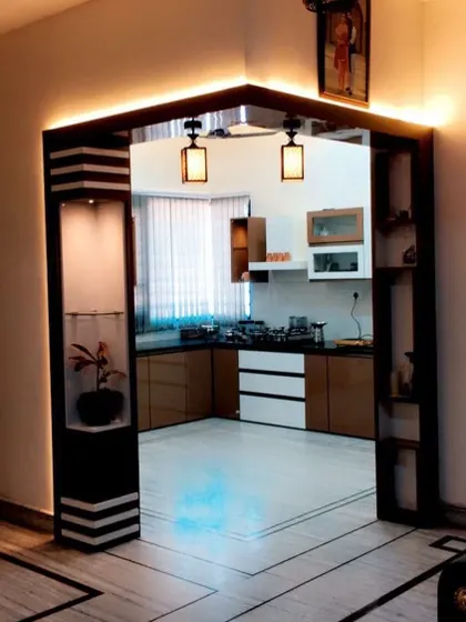 An elegant entrance to a kitchen, framed by a custom-built partition with integrated lighting and display niches. This adds a grand and welcoming feel to the kitchen area.