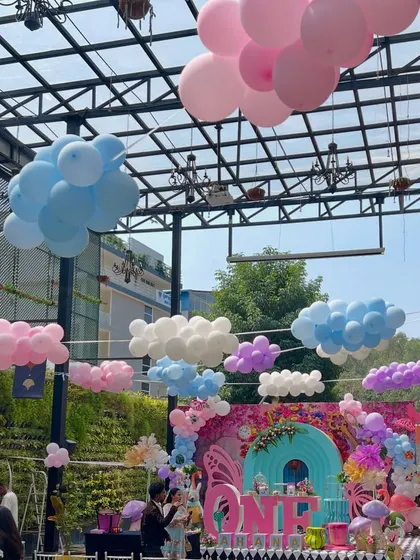 An outdoor 'Onederland' setup with balloon clouds floating above the main stage. This created a dreamy, surreal sky for Ahana's magical first birthday celebration.