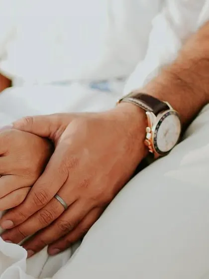 A close-up detail shot of a couple's hands gently held together during their pre-wedding yacht shoot, symbolizing their connection.