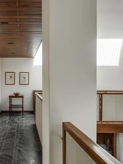 The upper-level corridor and skylit bridge. We used paneled walls and a wooden ceiling to add texture and detail, while the bridge connects the private areas of the home across the double-height living space.