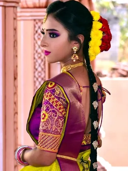 This profile shot highlights a traditional long braid decorated with jasmine and colored flowers. This type of hairstyling is an essential part of the complete South Indian bridal look.