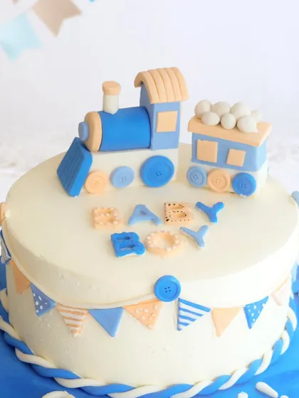 All aboard for baby joy! A playful train-themed cake to celebrate a baby boy's arrival, with cute button and banner details.