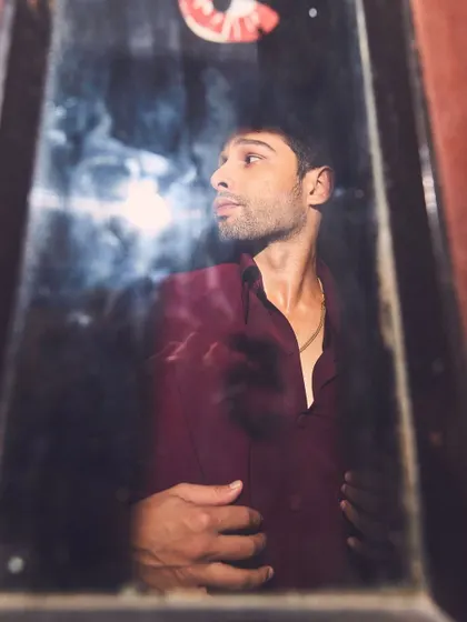 A more artistic, moody shot of Siddhant. The reflection and shadows add a layer of mystery to the rich color palette of his outfit.