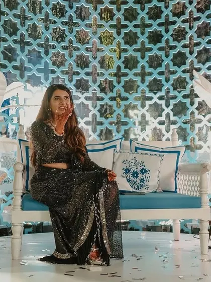 The bride, Yasha, at her Bar Palladio-inspired Haldi. The backdrop features a custom-cut 'jaali' screen and handcrafted sholawood flowers, all in a beautiful blue and white palette.