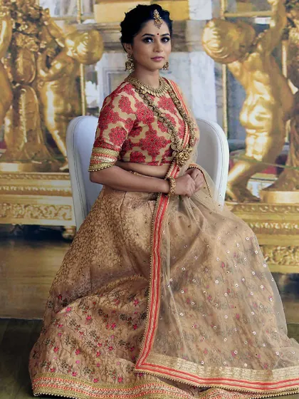 A full view of the sublime cream and red bridal lehenga, showcasing its graceful fall and detailed craftsmanship. This design is ideal for the bride who seeks a sophisticated and classic look.