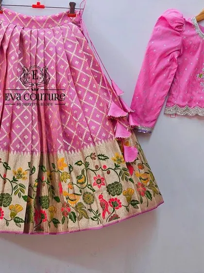 A similar long-sleeved lehenga design in pink. The skirt features a beautiful woven floral border.