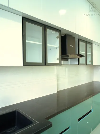 A close-up of the upper cabinets, which feature black-framed glass doors. This detail breaks up the solid white expanse and ties in with the black handles and countertop for a cohesive look.