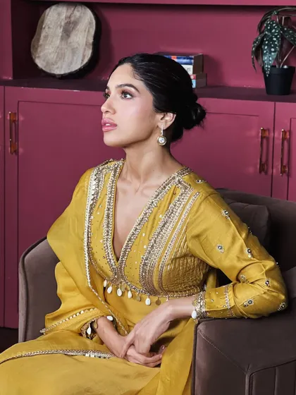 A seated portrait of Bhumi in her birthday outfit. The elegant updo and pearl drop earrings complete this regal look.