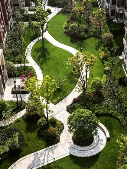 An aerial view of a large-scale commercial or residential landscape project. The design features meandering pathways, circular lawns, and strategically placed trees to create a park-like environment.