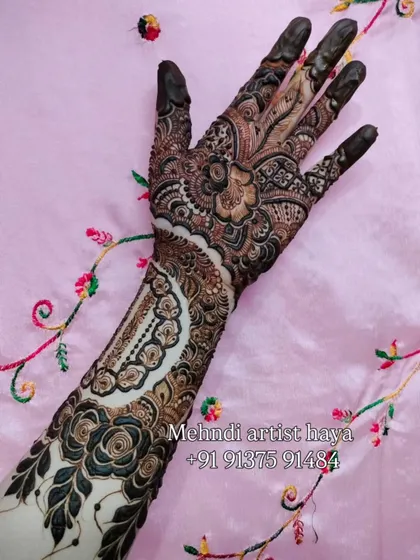 A unique bridal design featuring a large, intricate cuff on the forearm with negative space, paired with bold floral work on the hand.