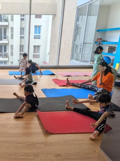 A wide shot of our flexibility class in our sunlit studio. Students of various ages are working on different stretches on their mats, each at their own pace.