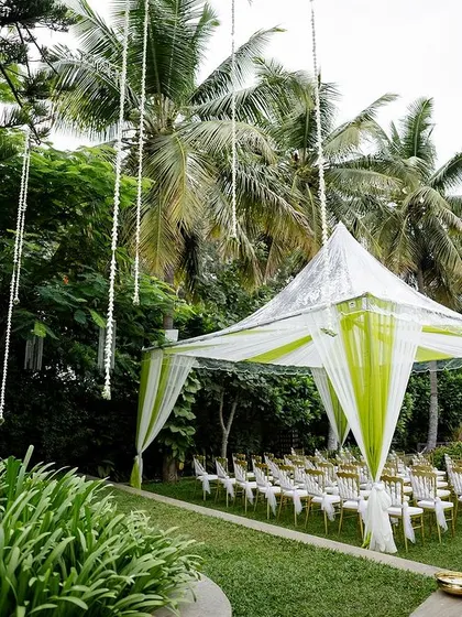 Another perspective of the rainproof tent and seating arrangement. The hanging floral streamers from the trees add a whimsical touch to the practical and beautiful setup.