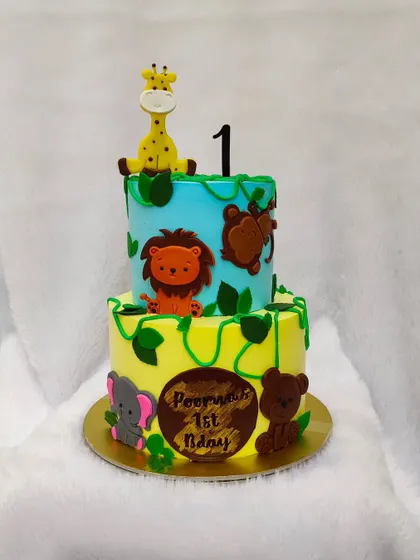 This two-tier jungle animal cake is perfect for a first birthday. It features cute fondant animals like a lion, giraffe, and elephant climbing on the tiers.