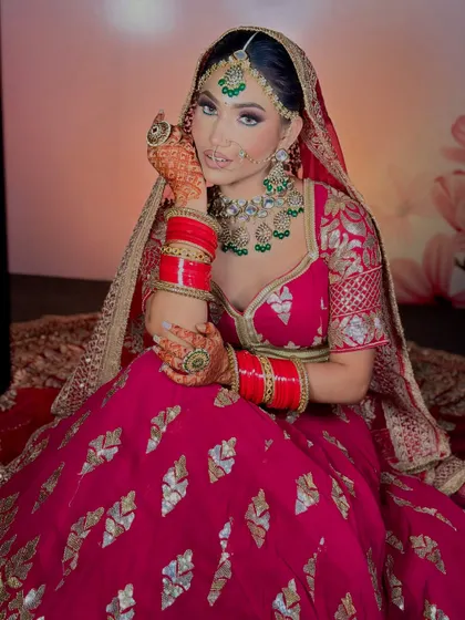 A beautiful bride in a magenta lehenga. The makeup features a soft pink and purple eye look to match her outfit, along with flawless, glowing skin.