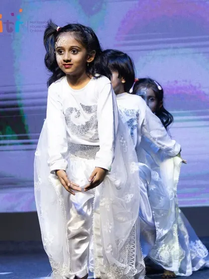 A line of dancers in white costumes, representing the gentle breeze. The unity in their performance is a result of weeks of practice.