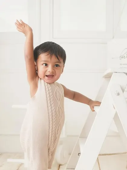 Waving to all his fans. This little one is celebrating his first birthday in style, standing tall and happy.