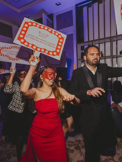 Guests in masks holding up fun placards, leading the couple into their after-party. It's all about creating a fun, immersive experience.