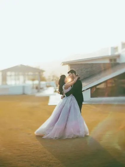 A romantic, sun-drenched photo of a couple embracing on a lawn, the golden hour light creating a beautiful, warm glow.