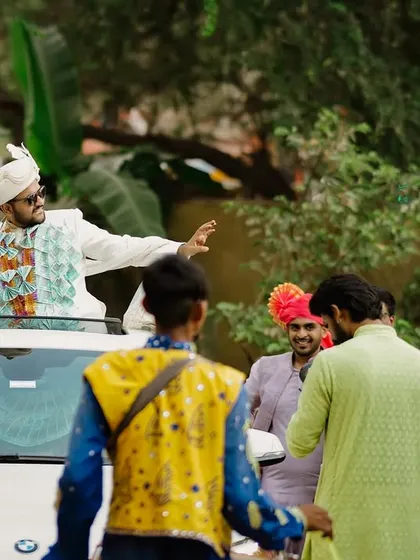 The groom's grand entry! Standing up through the sunroof of his car, the groom dances his way into the wedding venue, full of energy and excitement for the day ahead.