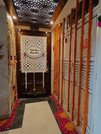 An elegant entrance decoration for a home. The door is decorated with marigold garlands and a custom nameplate for the couple, creating a personalized welcome.