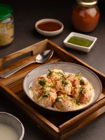 A wider angle of the dahi vada, showing the accompanying chutneys and ingredients. This shot provides more context and highlights the freshness of the dish.