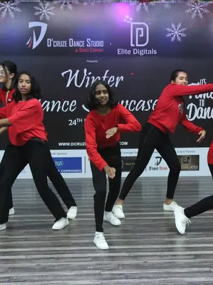 The group hits another pose in their energetic routine, showcasing their coordination and stage presence.