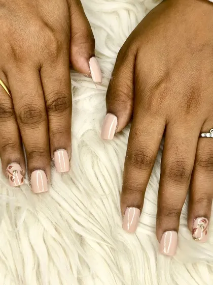 An elegant nude polish on short square nails, featuring a subtle leopard print accent nail with gold foil details.