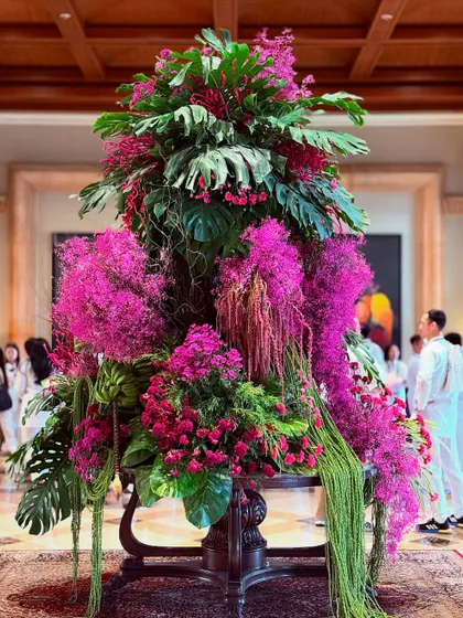A full view of the pink and green tropical installation, showcasing its dramatic height and lush, cascading form. This is what I mean by living art, a piece that has presence and movement.