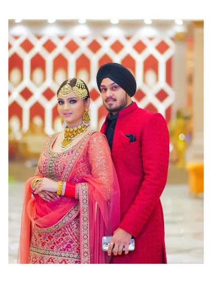 A stylish portrait of the couple, showcasing their coordinated red and black outfits. The modern, geometric background adds a contemporary feel to the image.