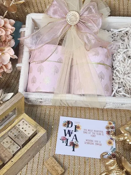 This charming Diwali hamper includes a rustic white basket, patterned jars, and a vintage style wooden domino set for some festive fun.