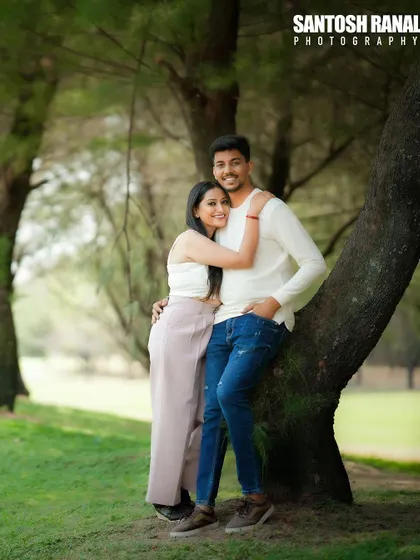 A sweet and relaxed portrait of a couple hugging by a tree in a park.