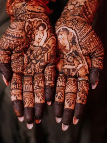 A close up of a bridal design featuring portraits of Radha and Krishna. Incorporating spiritual figures is a beautiful way to add a layer of divine blessing and personal faith to your wedding henna.