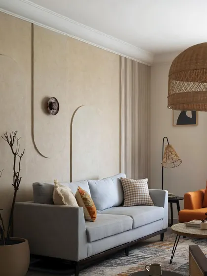 Another view of the minimalist living room, highlighting the large rattan pendant light and the sculptural dried branches, which bring natural elements into the space.