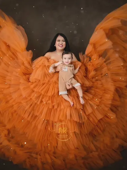 A beautiful portrait of mother and baby surrounded by the vibrant orange fabric. The sparkling effects add a touch of magic to this fine-art photograph.