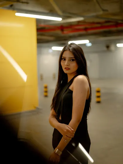 A moody portrait taken in an underground parking garage. The ambient lighting and the raw, concrete background create an edgy and modern fashion look.