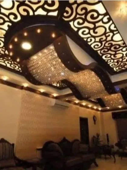 A truly breathtaking ceiling design featuring a massive, wave-like crystal chandelier set against a dark, curved structure with backlit jali work. This is the pinnacle of luxury.
